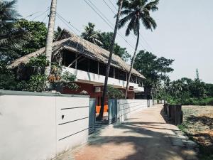 a house with a white fence and palm trees at Kuma Surf House in Kappil +41 photos