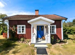 ein kleines rot-weißes Haus mit einer blauen Tür in der Unterkunft Hus Bohult in Berga