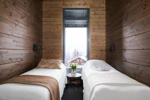 twee bedden in een kamer met houten wanden bij Villa Aspen D Ski-in Ski-out by Aavalevi in Levi