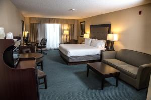 a hotel room with a bed and a couch and chairs at Holiday Inn Express & Suites Detroit - Novi by IHG in Novi