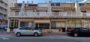 two cars parked in front of a building with a balcony at Casa Paseo in Torrevieja