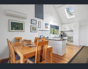 une cuisine et une salle à manger avec une table et des chaises en bois dans l'établissement The Cove, à Huon Island