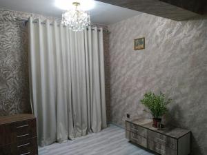 een woonkamer met een kroonluchter en witte gordijnen bij Дом хай-тек in Toshkent-Passajir Bekati