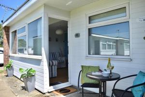 een patio met een tafel en stoelen en een raam bij 46 Hectors, Sunbeach, Scratby - Two bed chalet, sleeps 4, pet friendly, free Wi-Fi, free entry to onsite clubhouse and bed linen and towels included in Great Yarmouth