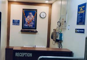 a clock on a wall with a picture of a man at Arihant palace in Shirdi