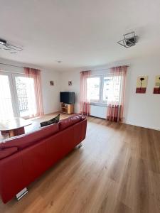 a living room with a red couch and wooden floors at ferienwohnung natalie in Nickenich