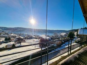 a view of a snow covered city from a glass building at Chalet La Souris, chaleureux avec vue panoramique in Gérardmer