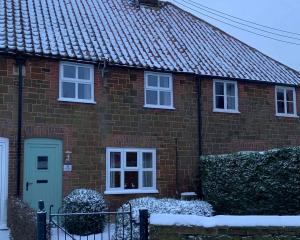 a red brick house with a blue door and snow at Pollywiggle Cottage, Dog Friendly cottage in Heacham in Heacham