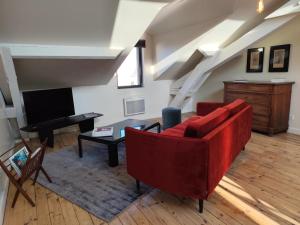 a living room with a red couch and a piano at le marais in Romans-sur-Isère +5 photos
