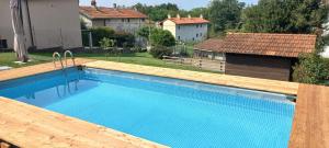 a large swimming pool with a wooden deck and a house at Country Corner Lago Maggiore in Divignano