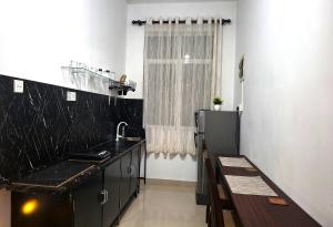 a kitchen with black counters and a sink and a window at Zeleny Retreat Home Stay in Matara