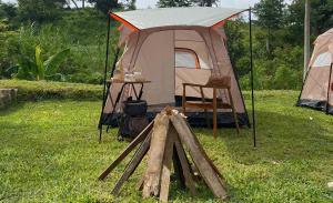 ein Zelt mit einem Tisch und einem Stuhl im Gras in der Unterkunft The Valley House Ci Dwi Resort in Subang + 5 Fotos