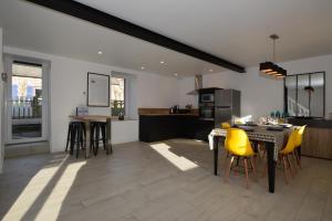 a kitchen and dining room with yellow chairs and a table at Gite Cour du Bourg - Baie du Mont Saint Michel in Cherrueix