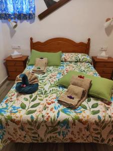 a bed with green pillows and towels on it at Casa Vacacional Lupe in Vallehermoso