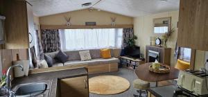 a living room with a couch and a table at Bittern 22, Parkdean, California Cliffs, Scratby, sleeps 6, free wi-fi, bedding and towels included, 5 mins from beach in Great Yarmouth