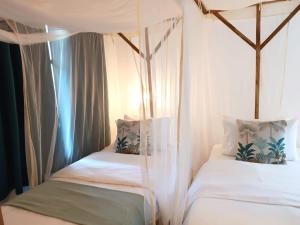 a bedroom with two beds with white sheets at Peace and Love Garden in Mto wa Mbu