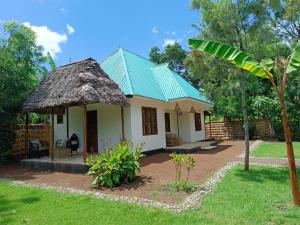 a small white house with a green roof at Peace and Love Garden in Mto wa Mbu