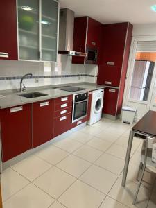 a kitchen with red cabinets and a washing machine at Piso El almendro Lerma in Lerma