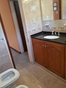 a bathroom with a toilet and a sink and a mirror at Lo de ROLO in Huerta Grande
