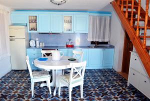 a kitchen with blue cabinets and a white table and chairs at Villa Blu Majestic beach villa in Halki