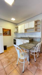 トーレスにあるFlat 100m da praia, vista mar com garagem, central e completo!のキッチン(テーブル、椅子、カウンター付)