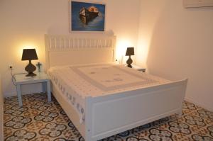 a white bed in a bedroom with two lamps at Villa Blu Majestic beach villa in Halki