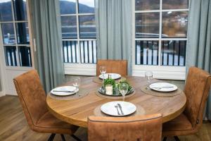 a wooden table with chairs and plates and wine glasses at Amberfish in Tromsø