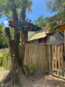 a sign on a tree next to a fence at Pousada Casa do Nilo in Ilha do Mel