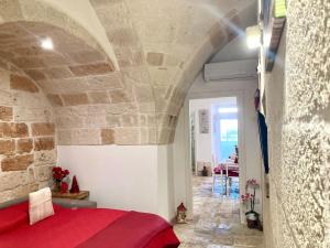 a bedroom with a red bed and a stone wall at Antica Pietra in Polignano a Mare