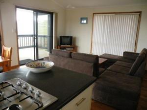 a kitchen with a stove and a living room at Waves & Wildlife Cottages Kangaroo Island in Stokes Bay