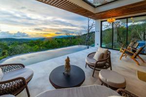 a patio with chairs and a table and a pool at Luxury villa on the Cloud Forest Infinity Pool in Monteverde Costa Rica