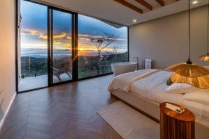a bedroom with a large window with a bed and a tub at Luxury villa on the Cloud Forest Infinity Pool in Monteverde Costa Rica +20 photos