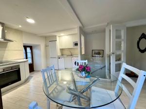a dining room with a glass table and white chairs at Casa Tía Milagros in Puebla de Sanabria