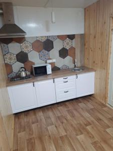 a kitchen with white cabinets and a tile wall at Villa Opir in Skole