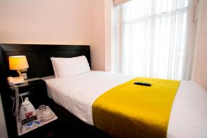 ein Schlafzimmer mit einem großen Bett und einer gelben Decke in der Unterkunft Bloomsbury Palace Hotel in London