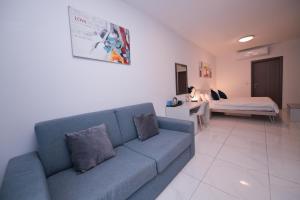 a living room with a blue couch and a bed at The Exiles Hotel in Sliema