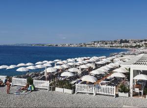 a bunch of umbrellas on a beach with the ocean at Syrah - Cozy Apartment in Nice