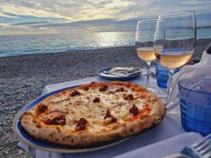 a pizza on a table with two glasses of wine at Syrah - Cozy Apartment in Nice