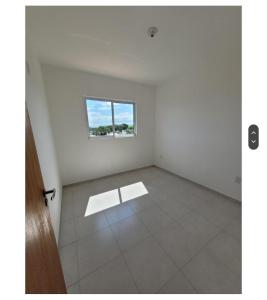 una stanza vuota con una finestra su un muro bianco di Apartamento grande a Navegantes