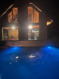 a house at night with a pool in front at Strefa Ciszy Bieszczady domki z jacuzzi lub z banią z hydromasażem in Terka