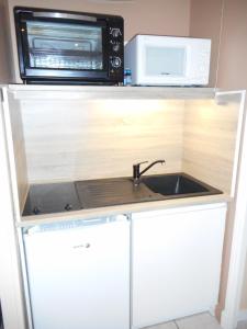 een keuken met een spoelbak en een magnetron bij Aux Cottages du port Honfleur in Honfleur