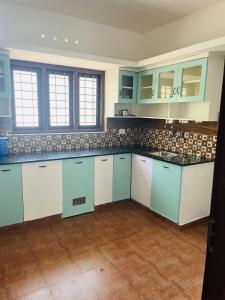 cocina con armarios azules y blancos y suelo de madera en Trivi Chackai Home Stay, en Trivandrum