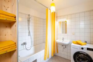 bagno con vasca, lavandino e lavatrice di Apartments Sopherl - by myNests ad Aich