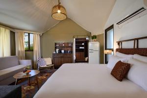 a bedroom with a large white bed and a living room at כפר נופש דוגה - ריזורט קסום על שפת הכנרת in Moshav Ramot