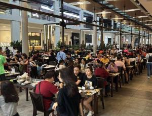 a group of people sitting at tables in a restaurant at Podium apartments in Kuching
