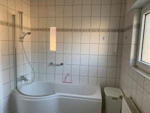 eine weiße Badewanne in einem Badezimmer mit Fenster in der Unterkunft Cozy Apartment - 2 BR, Spacious Kitchen, Balcony, Top Location in Hemsbach