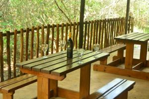 a wooden picnic table with a bottle of wine and glasses at Toad Tree Cabins in Sodwana Bay