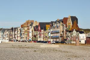 a row of buildings on the beach with cars parked at Villa Sans Souci - Beach 20m away in Mers-les-Bains
