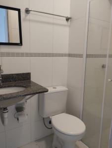 a white bathroom with a toilet and a sink at Itaguá - 1 quadra da praia, 2 quartos, 2 banheiros, acomoda 5 pessoas in Ubatuba
