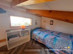 a small bedroom with a bed and a window at Cabañas Atardecer Fandango in Chaitén